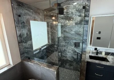 Frameless glass shower enclosure in a modern marble bathroom