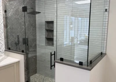 Frameless glass shower with matte black hardware on a knee wall