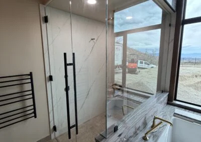 Frameless glass shower with a matte black ladder pull