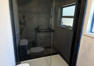 Frameless sliding shower door with black track in a bright bathroom