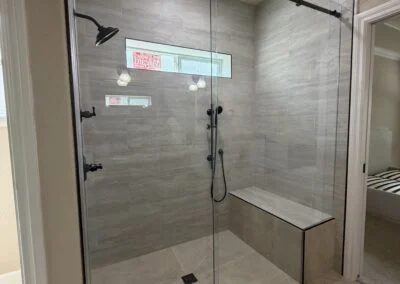 Frameless sliding shower door with matte black hardware in a tiled bathroom
