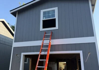 Gray two-story garage with new upper window and ladder