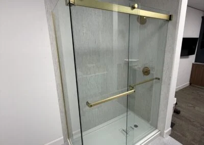 Sliding glass shower enclosure with brushed brass hardware