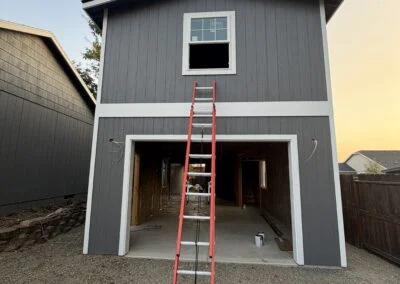 Two-story garage with a new upper window and ladder in front