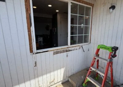 Window opening on a house exterior during replacement, ladder nearby
