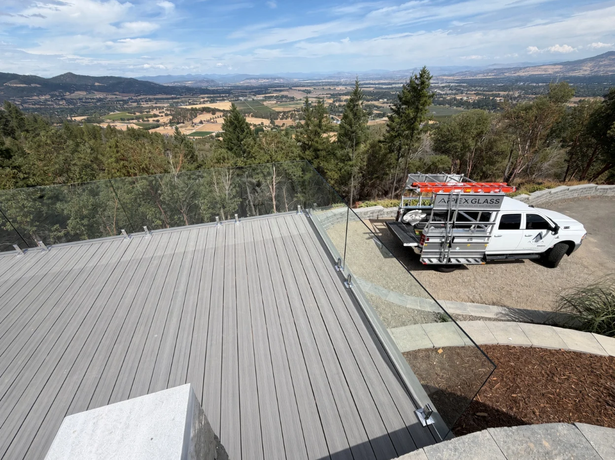 Deck with glass railing and a work truck parked below