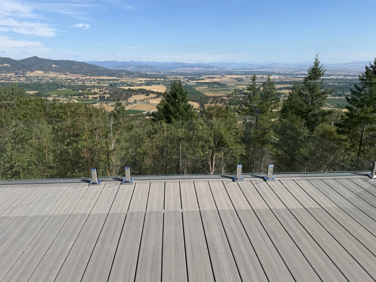 Frameless glass railing on a deck overlooking a wooded valley