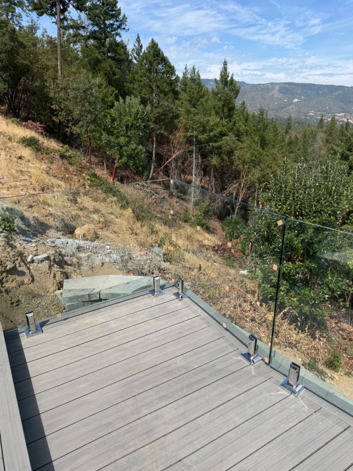 Glass railing along a deck edge above a forested hillside