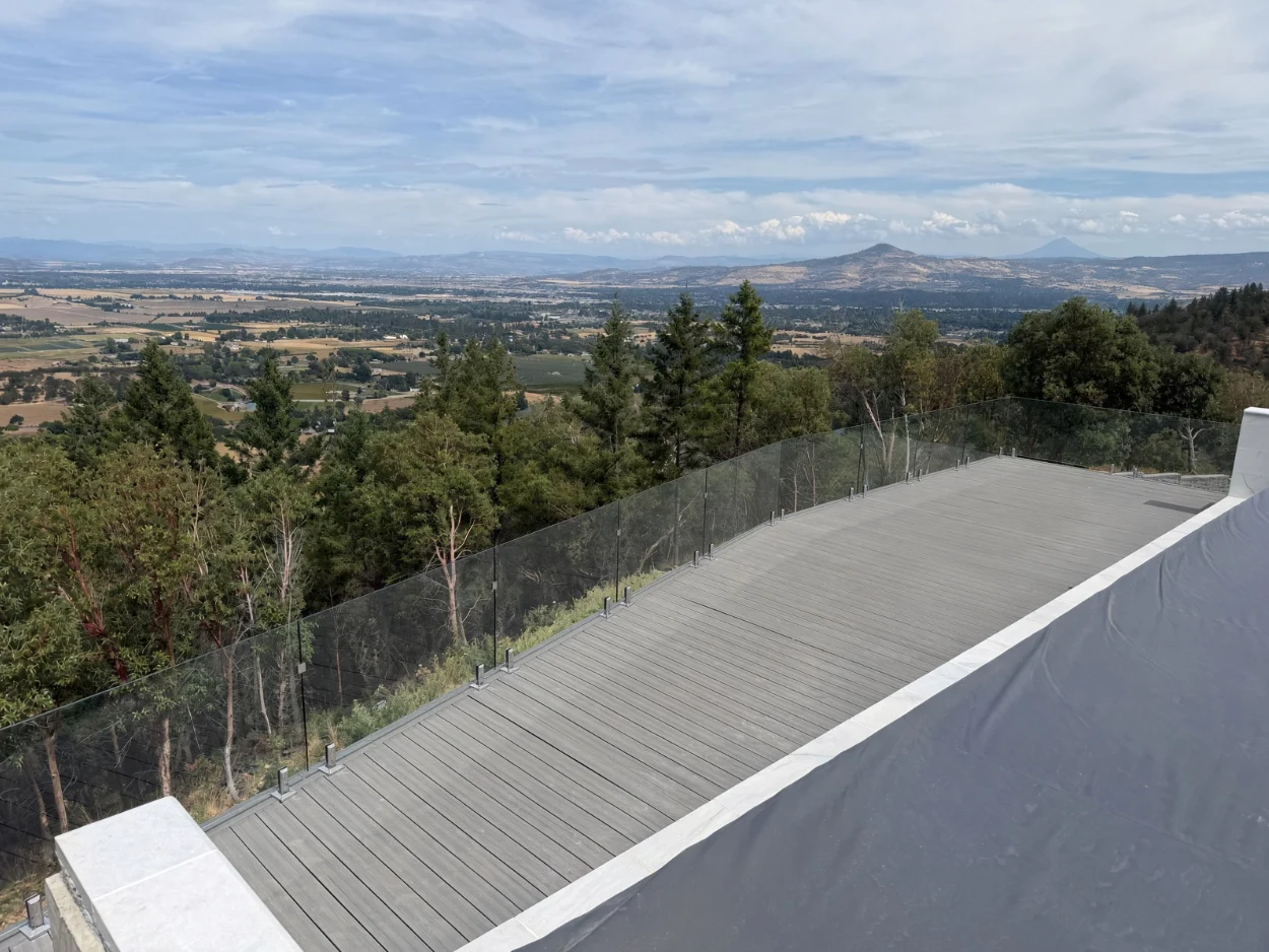 Glass railing wrapping a deck overlooking hills and valley